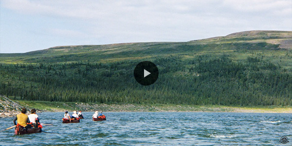 Several people in canoes on a river in the Northwest Territories.