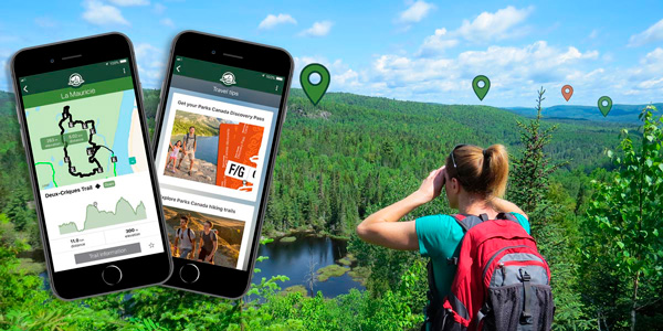 A young woman looks at the scenery in the distance while hiking. Phones show trail maps and travel tips available in the Parks Canada mobile app.