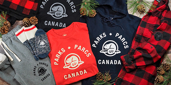Les produits dérivés de Parcs Canada disposés de façon festive avec des pommes de pin.