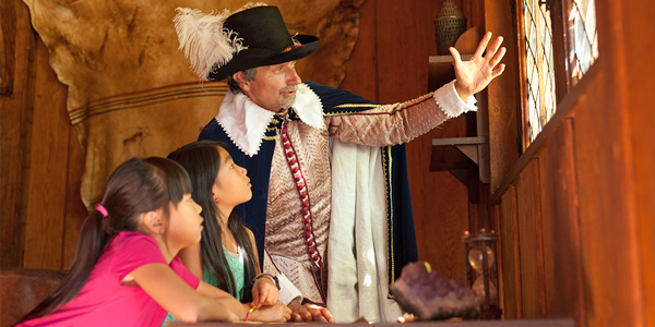 A guide interpreter in period costume speaks with young visitors at Port-Royal National Historic Site.