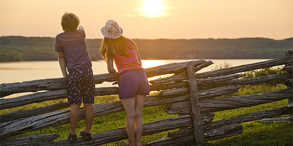 Deux enfants observent le coucher de soleil sur le lac au lieu historique national du Fort-Témiscamingue.