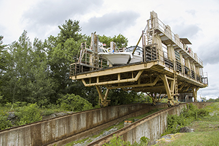 A boat sitting above train tracks inside chamber of marine railway descending hillside at Trent-Severn Waterway National Historic Site.