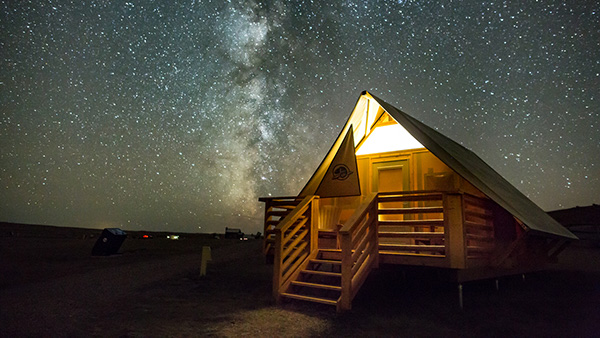 A Parks Canada oTENTik below the Milky Way at night in the Dark Sky Preserve at Grasslands National Park.