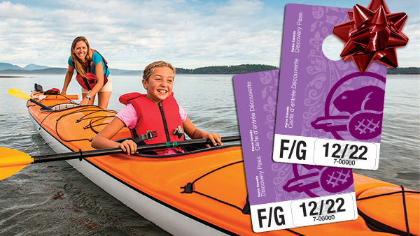 Des cartes d’entrée Découverte superposées sur une photo d’une jeune fille et de sa mère qui reviennent d’une sortie en kayak dans la réserve de parc national des Îles-Gulf.