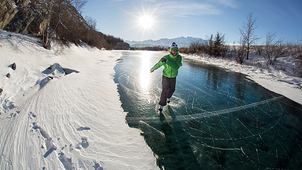 Un homme patine sur la glace naturelle au grand soleil à la pointe Disaster au parc national Jasper. 