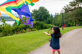 Une jeune fille fait voler un cerf-volant aux couleurs vives au lieu historique national Alexander-Graham-Bell.