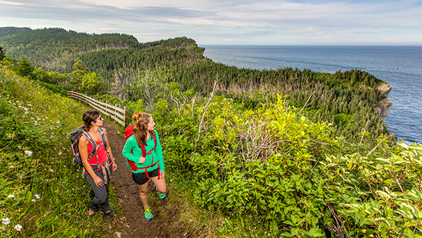 Deux femmes regardent la mer lors d’une randonnée sur le sentier Les Graves dans le parc national Forillon.